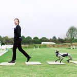 Magicdog Pro Roboterhund folgt elegant gekleidetem Mann draußen auf grüner Wiese